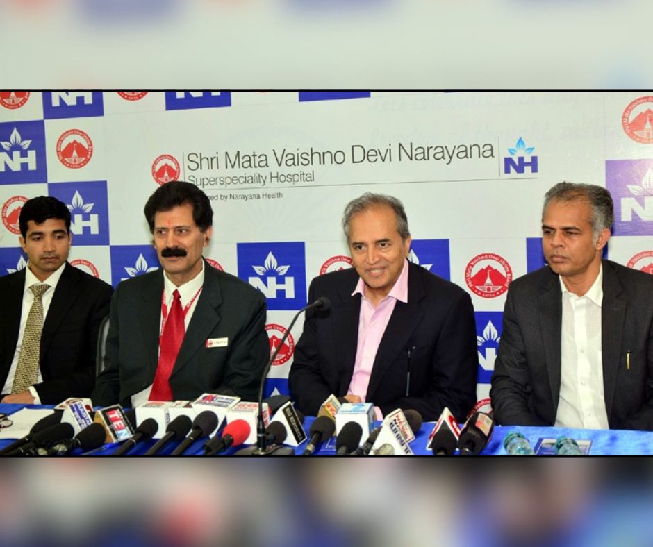 A panel of senior leaders seated behind a table with multiple media indicating a press briefing
